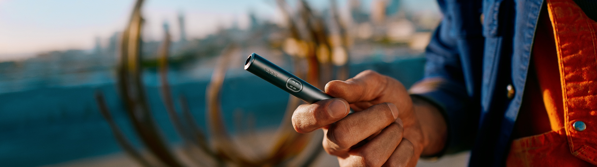 A person holding an IQOS ILUMA i prime Color Midnight Black